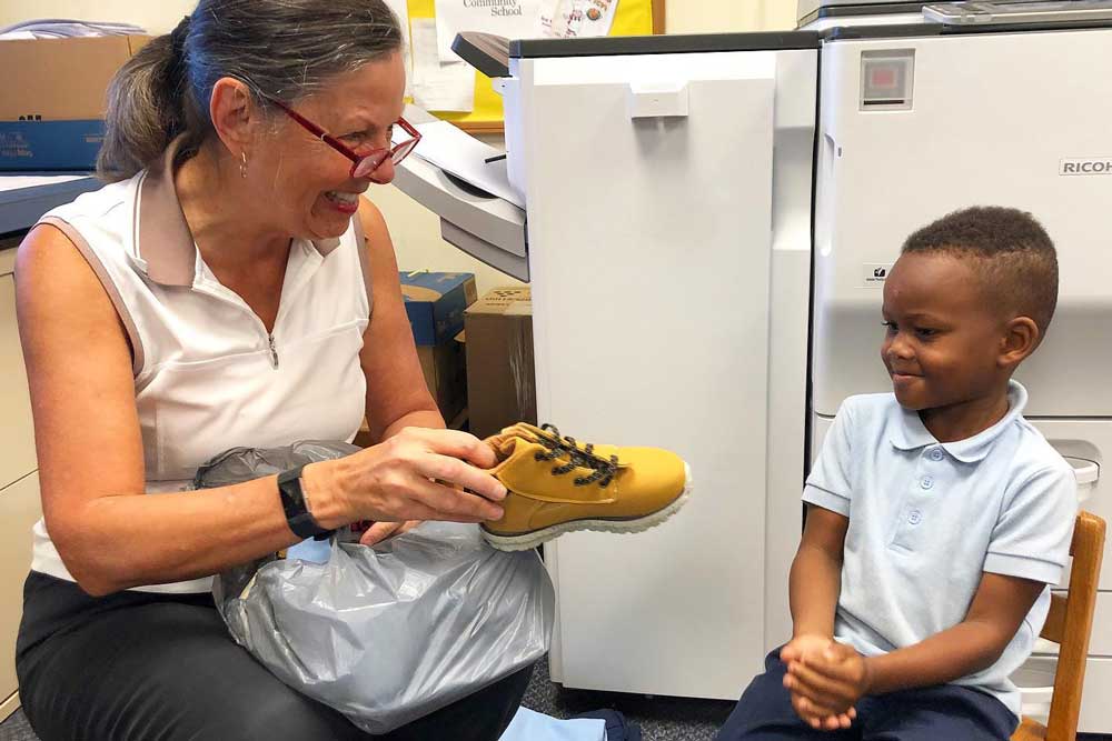 The Little Bit Foundation - volunteer giving shoes to young boy